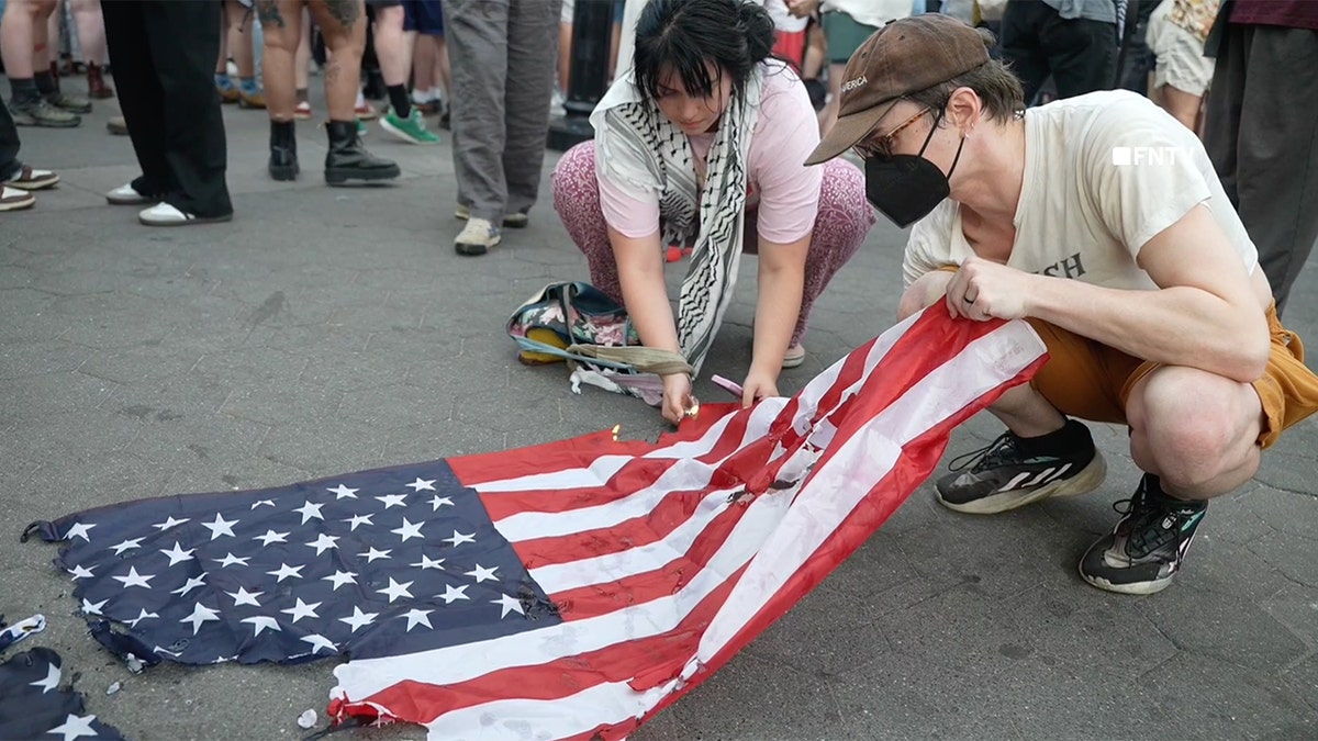 Una persona intenta prender fuego a una bandera estadounidense