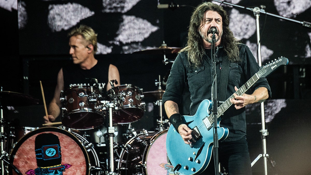 Foo Fighters Dave Grohl plays a bright turquoise guitar on stage In Denmark