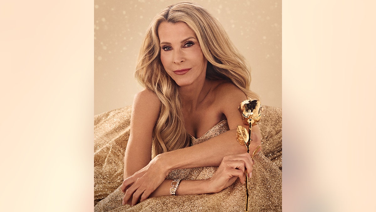 Joan Vassos in a gold gown hold a gold plated rose as the "Golden Bachelorette"