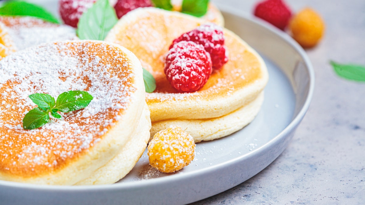 Se ve un plato de tortitas soufflé japonesas con frambuesas.