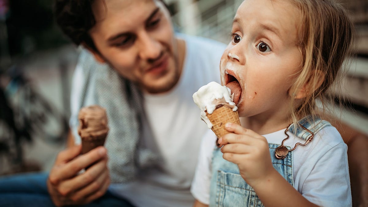 Man and child eating ice cream cones.