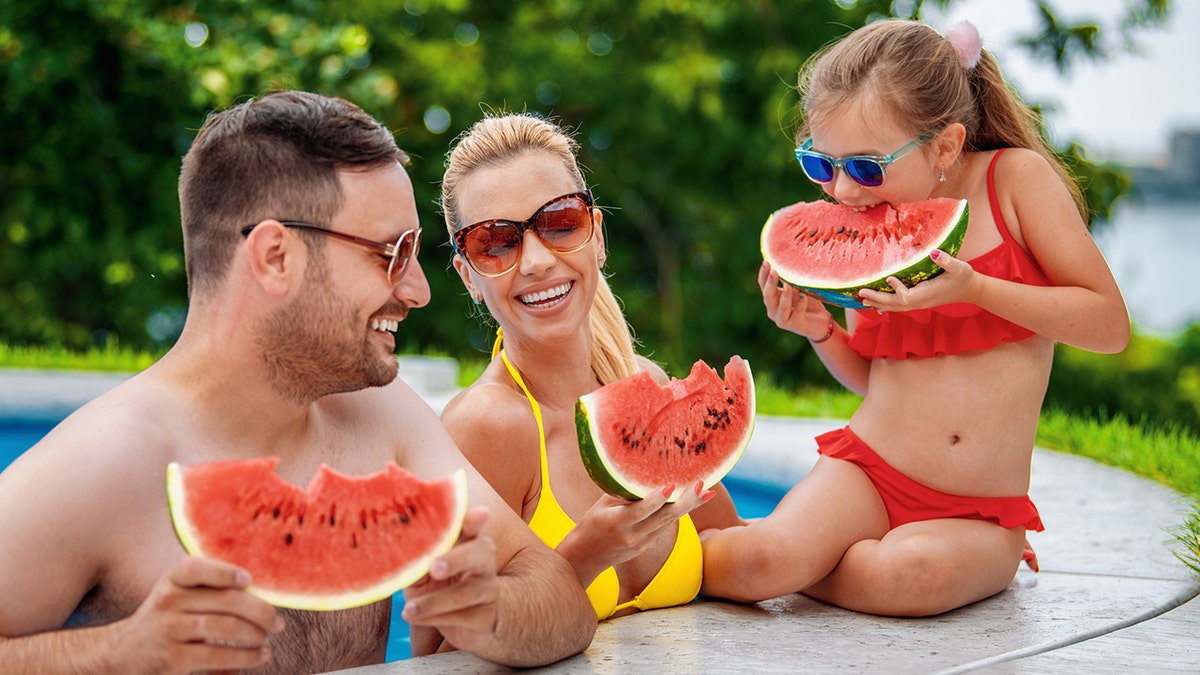 family eating watermelon poolside