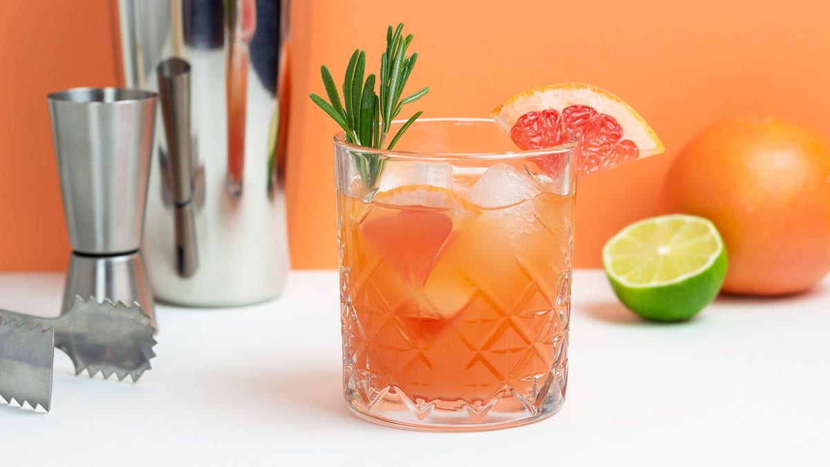 Paloma cocktail with rosemary sprig and grapefruit wedge.