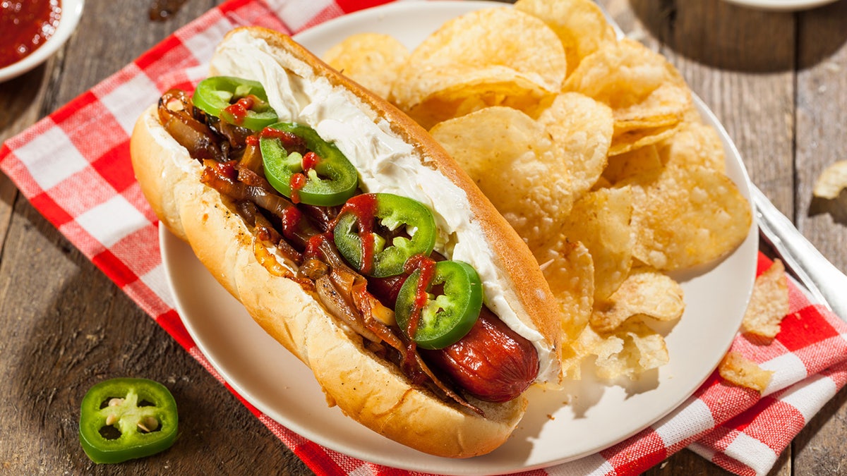 A Seattle-style hot dog with cream cheese on the bun, topped with grilled onions and jalapeno peppers.