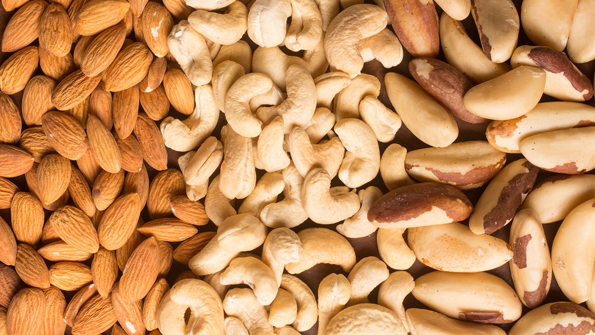 Almendra, anacardo y nueces de Para en forma de corazón sobre fondo blanco.