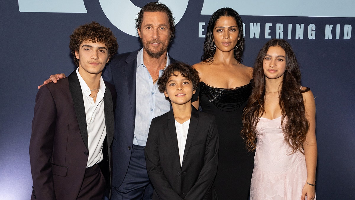 Matthew McConaughey and his wife Camila smile on the carpet with their three children: Levi, Livington, and Vida