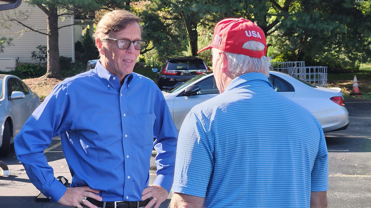 Mike Ramone speaks with a potential voter in a red hat