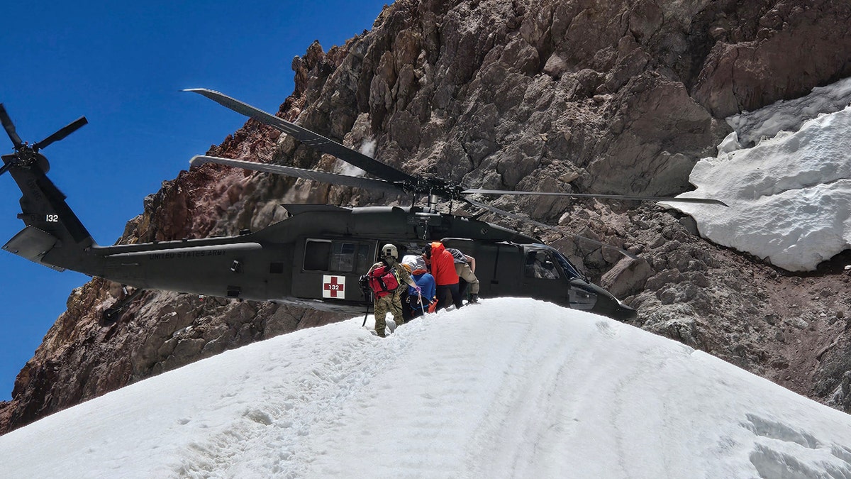 rescuers approaching National Guard helicopter on mountain