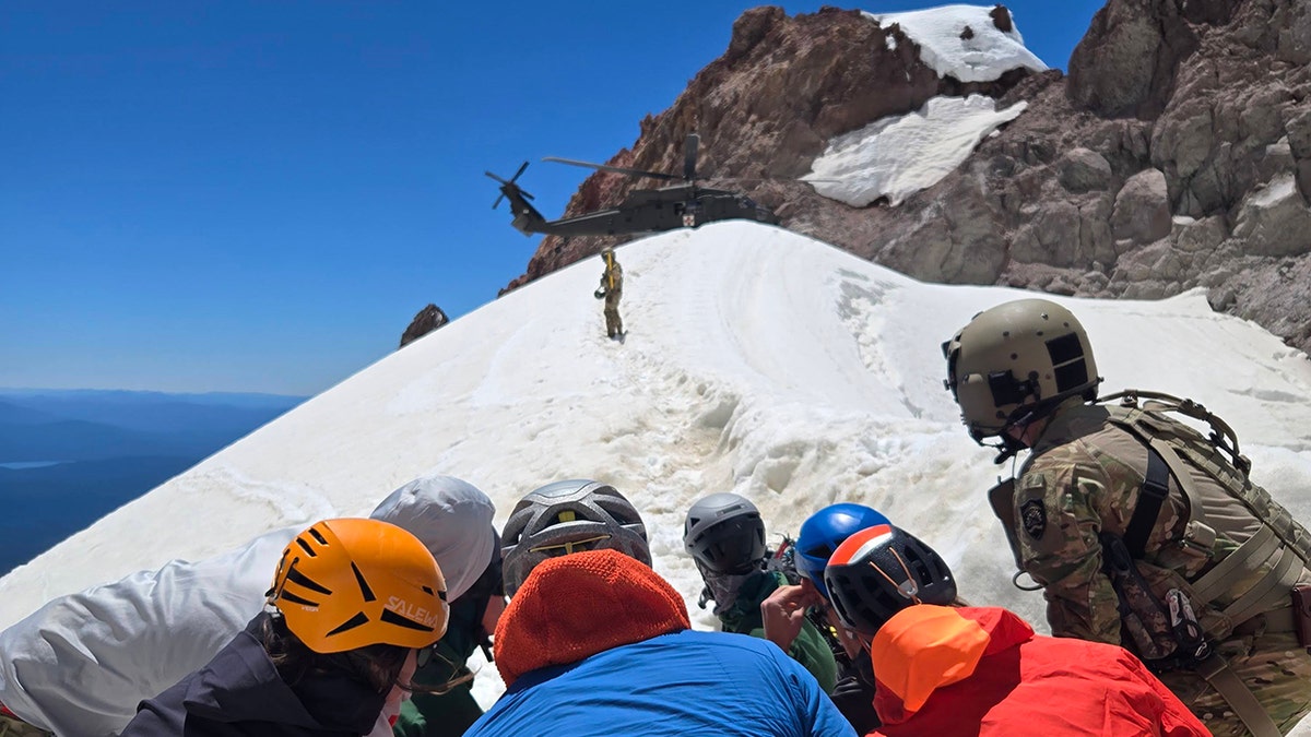 rescuers watching as National Guard helicopter lands on mountain