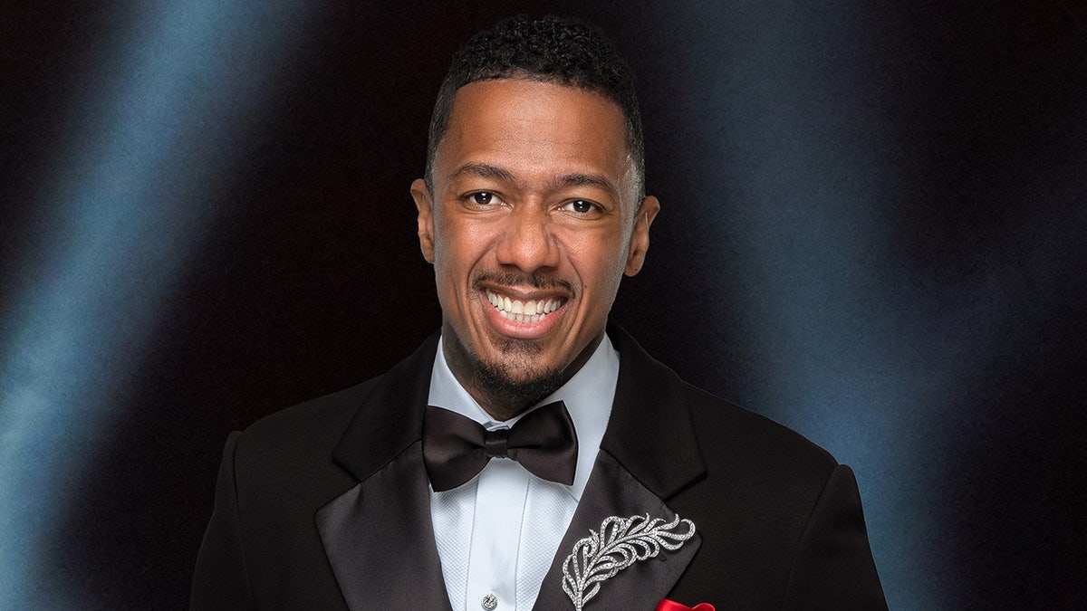 Nick Cannon smiling in a black tux