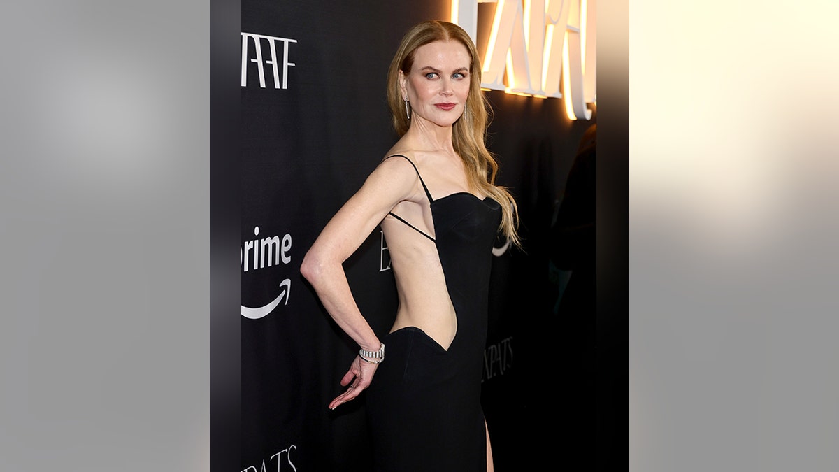 Nicole Kidman con un vestido negro se pone la mano en el culo mientras posa en la alfombra