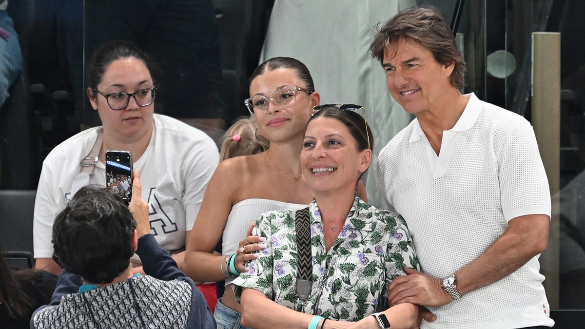 Tom Cruise poses for a photo with fans at the Olympics