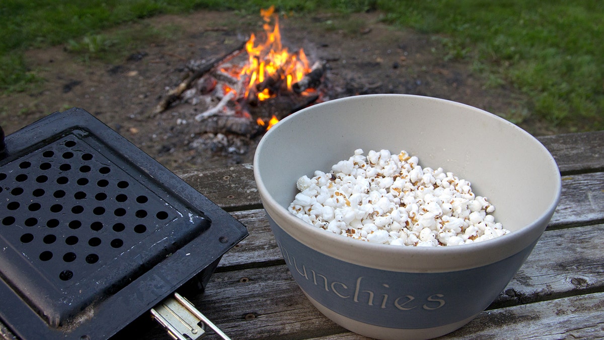 A bowl of popcorn near a campfire