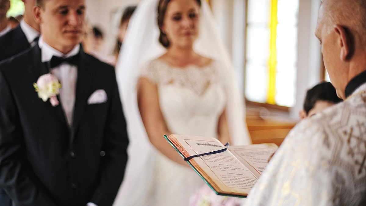 Priest reading from bible at marriage ceremony 