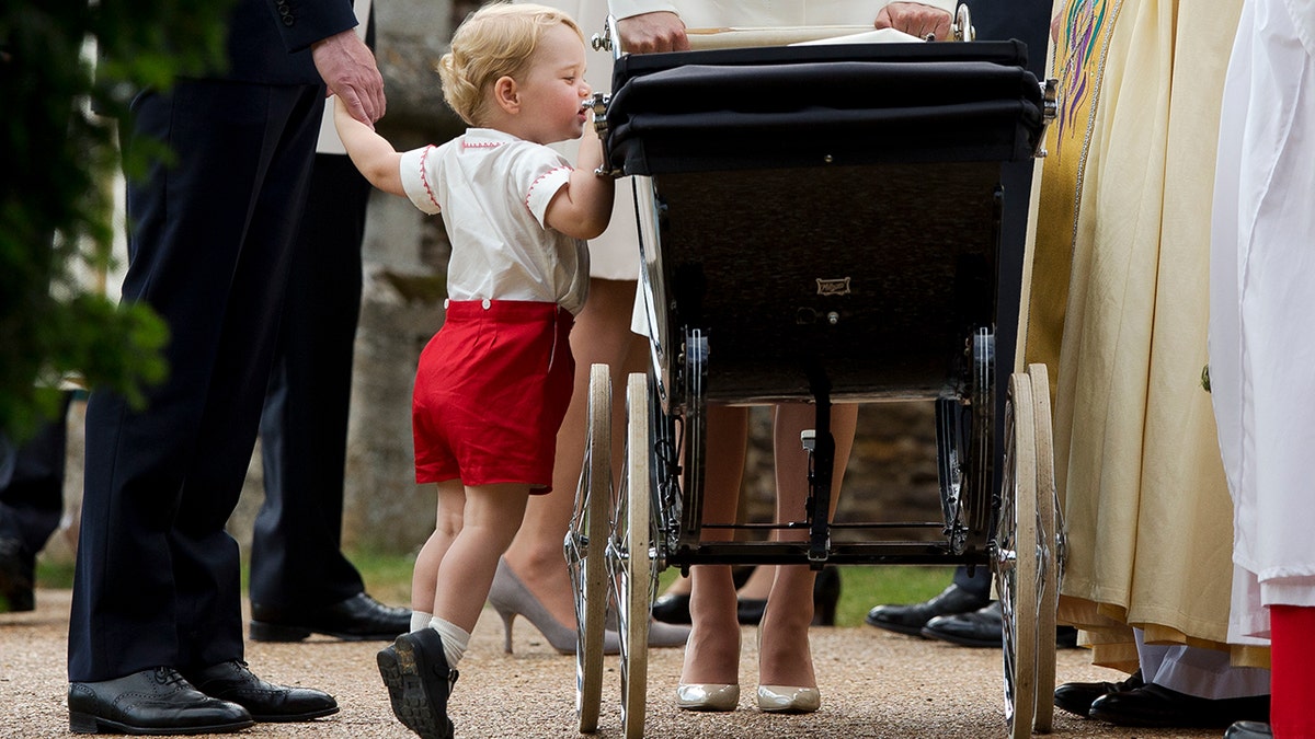 Prince George on his tip toes looking into Princess Charlotte's stroller.