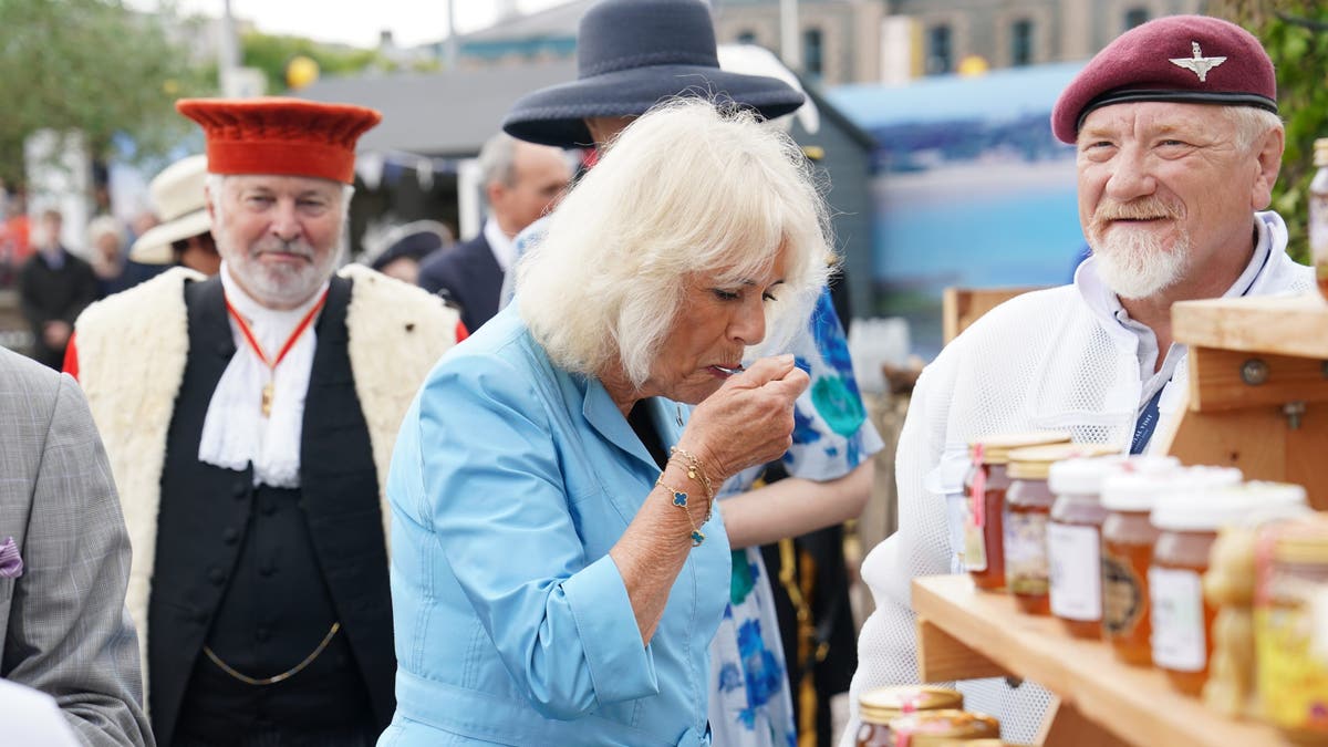 A photo of Queen Camilla tasting honey