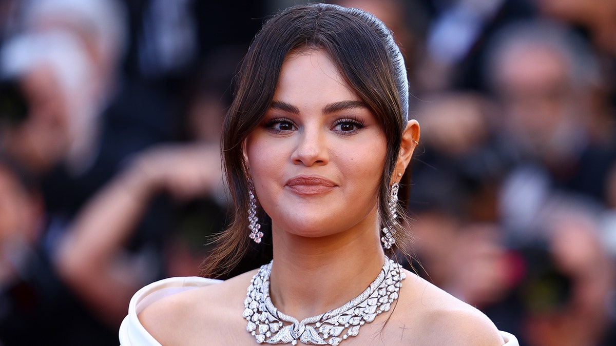 Selena Gomez in a strapless black and white dress walks the carpet at Cannes, wearing a massive diamond necklace