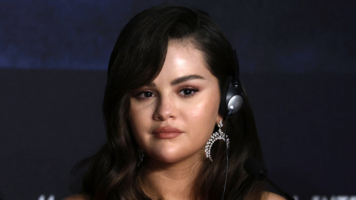 Selena Gomez with headphones on looks slightly perturbed in a photo taken at Cannes Film Festival
