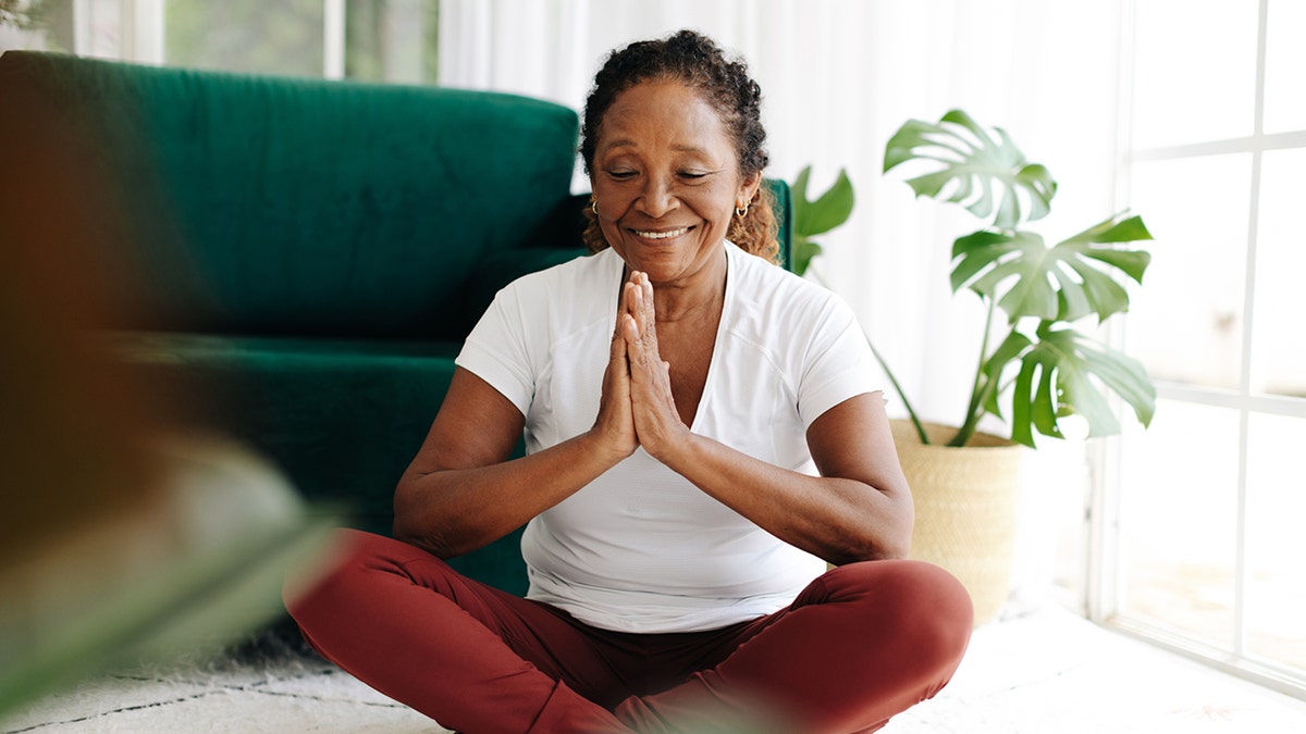 Una mujer mayor meditando en casa