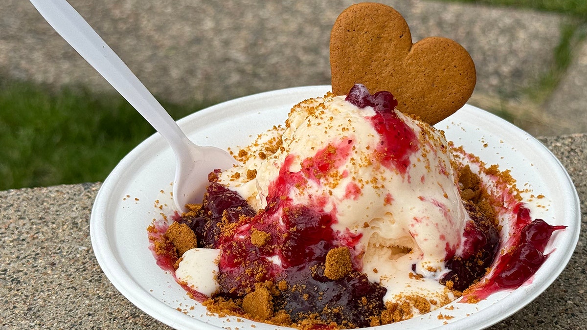 Ice cream sundae with lingonberries and a cookie garnish.