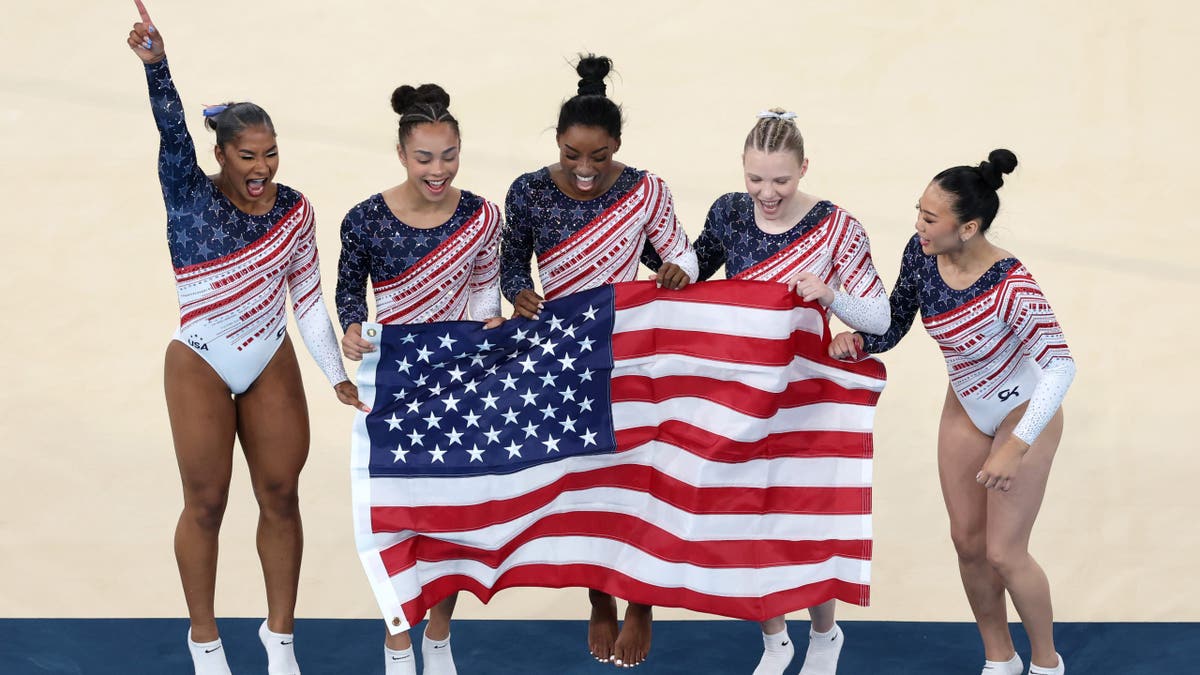 USA women's gymnastics team holding American flag