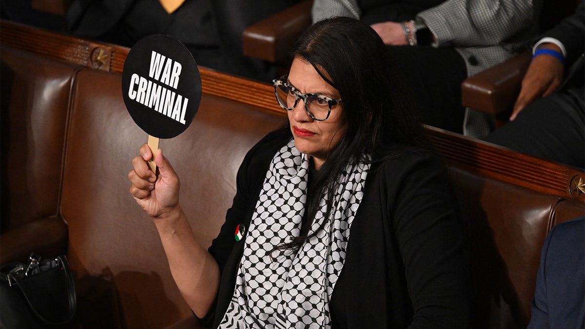 Rashida Tlaib holding a sign that says "War Criminal"