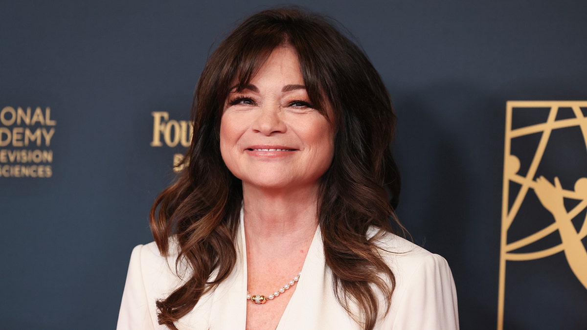 Valerie Bertinelli smiles in a white blouse on the carpet