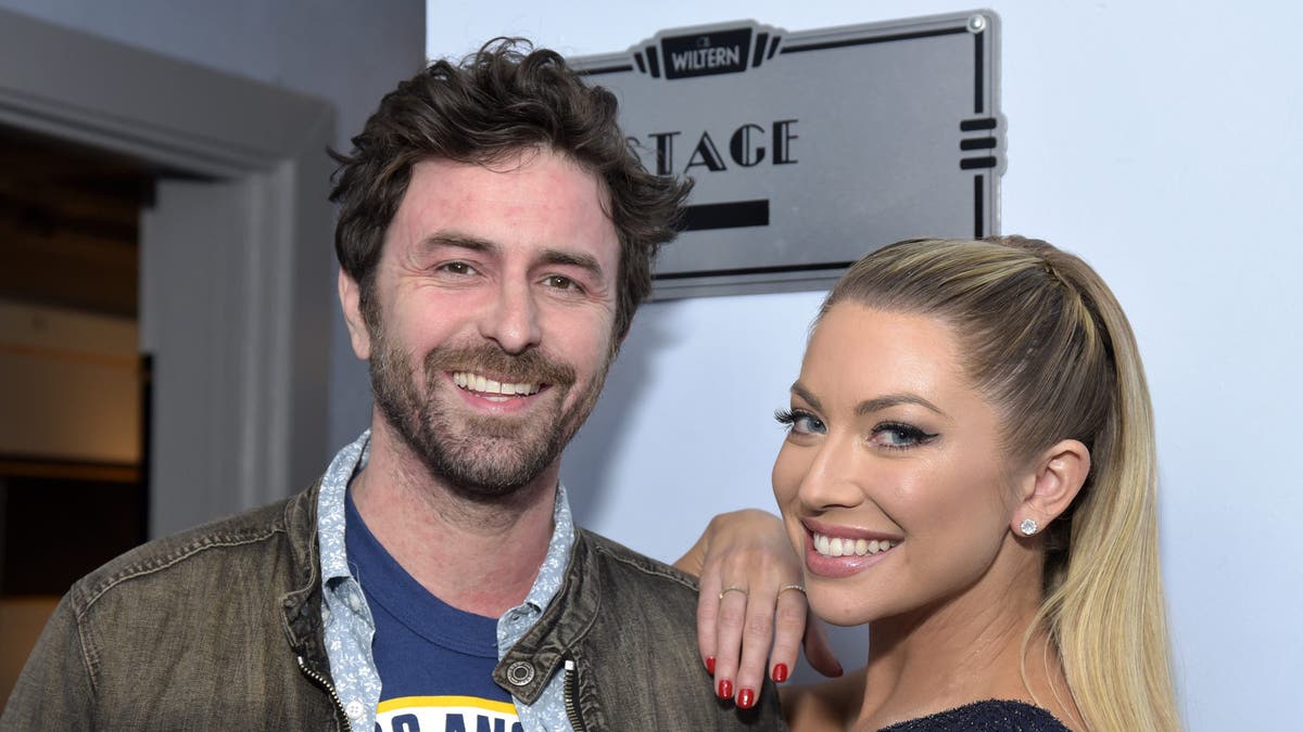 Beau Clark smiles for a photo with wife Stassi Schroeder who has her hand on his shoulder