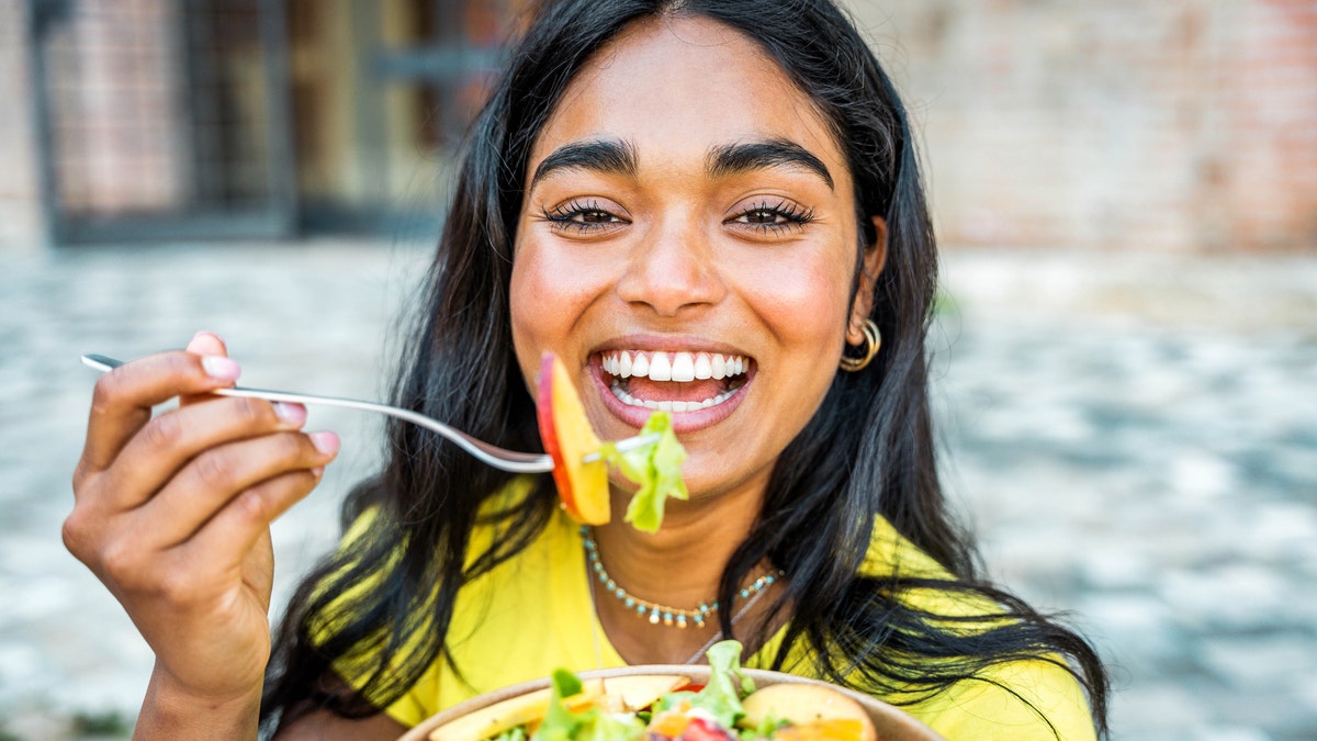 A happy woman eating salad