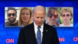 President Joe Biden looks downward on stage with images of voters behind him