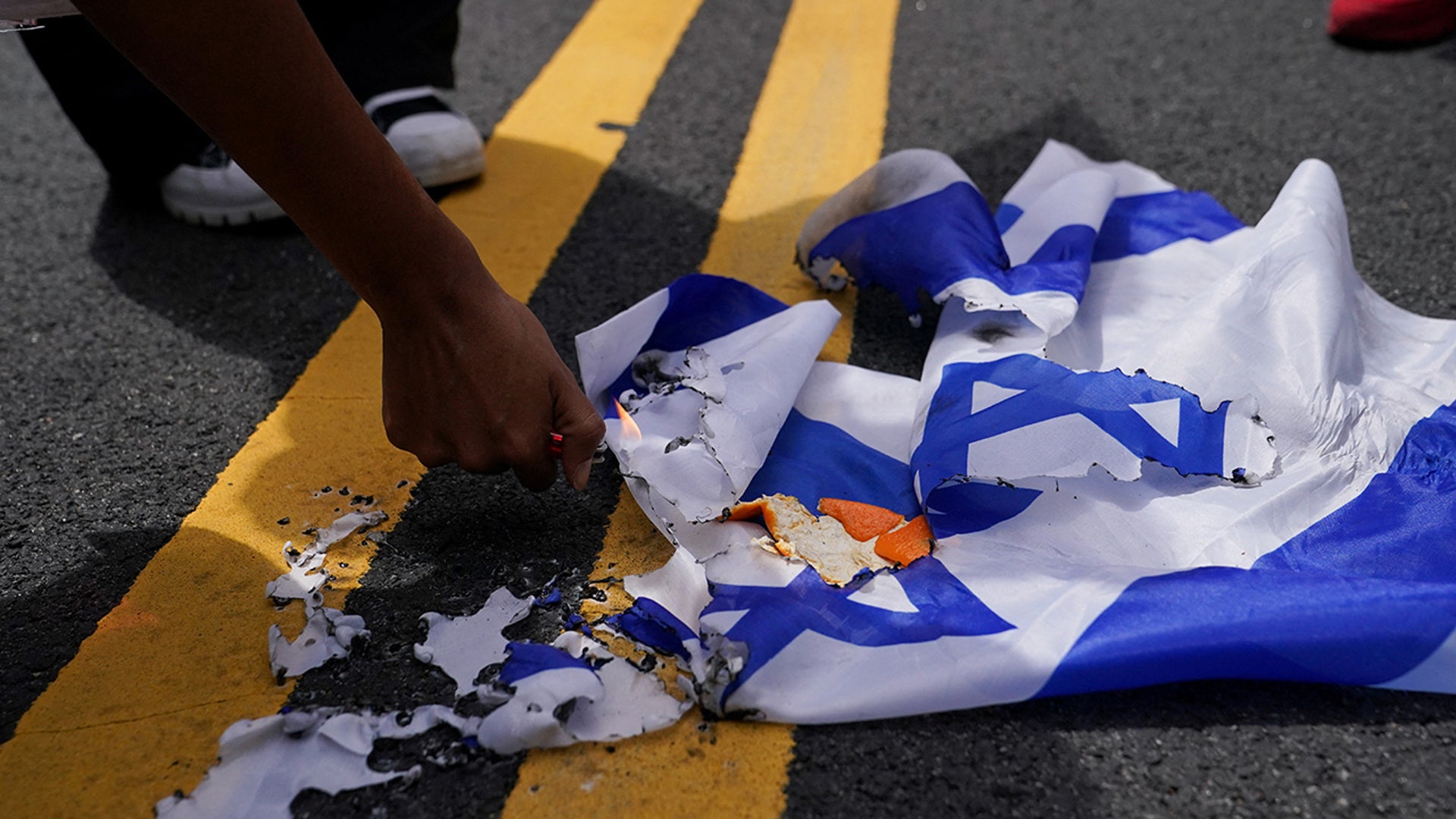 A pro-Palestinian demonstrator burns an Israeli flag, on the day of Israeli Prime Minister Benjamin Netanyahu's address to a joint meeting of Congress, on Capitol Hill in Washington, U.S., July 24, 2024. 