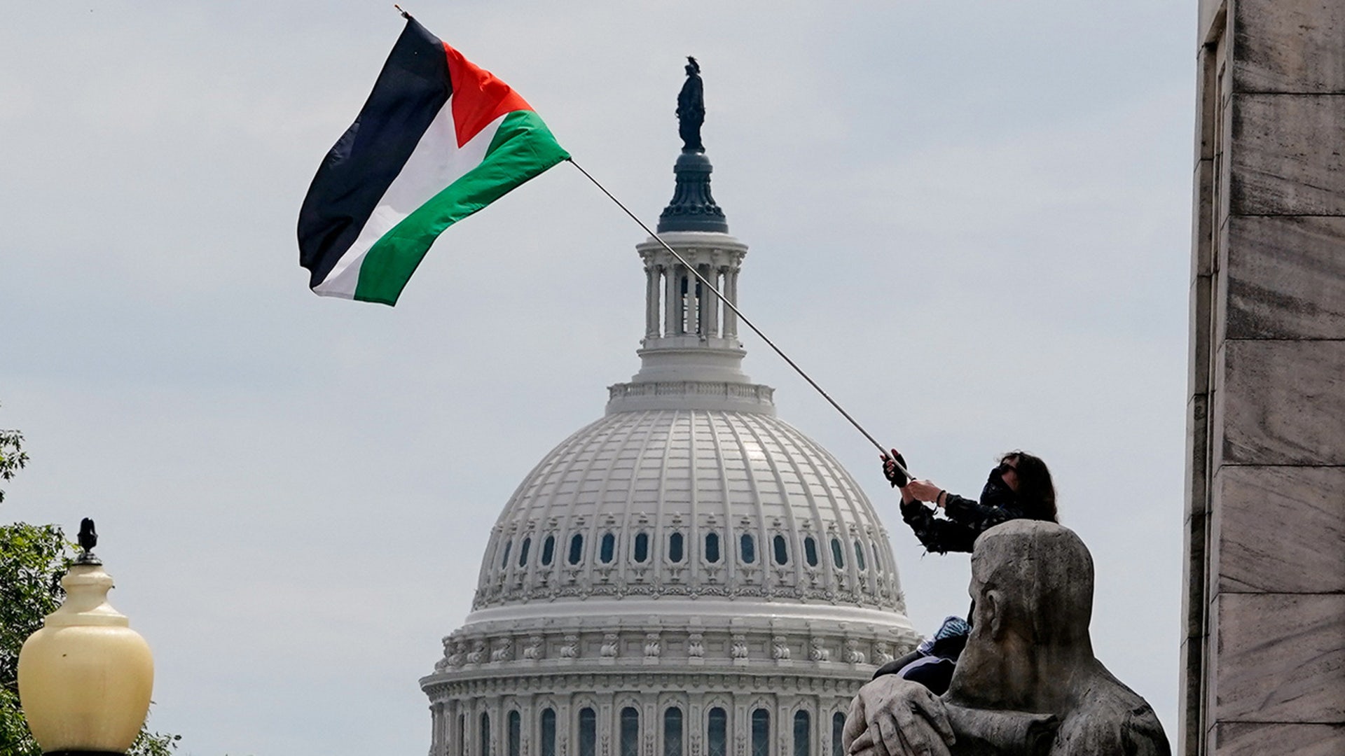 A pro-Palestinian demonstrator waves a Palestinian flag, with the Capitol dome seen in the background, on the day of Israeli Prime Minister Benjamin Netanyahu's address to a joint meeting of Congress on Capitol Hill in Washington, U.S., July 24, 2024. REUTERS/Nathan Howard