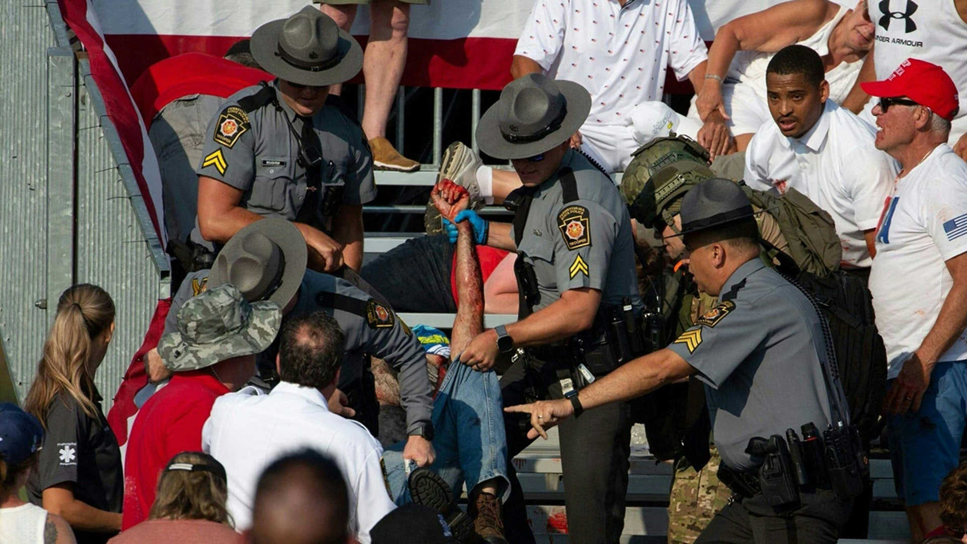 A person is removed by state police from the stands after guns were fired at Republican candidate Donald Trump