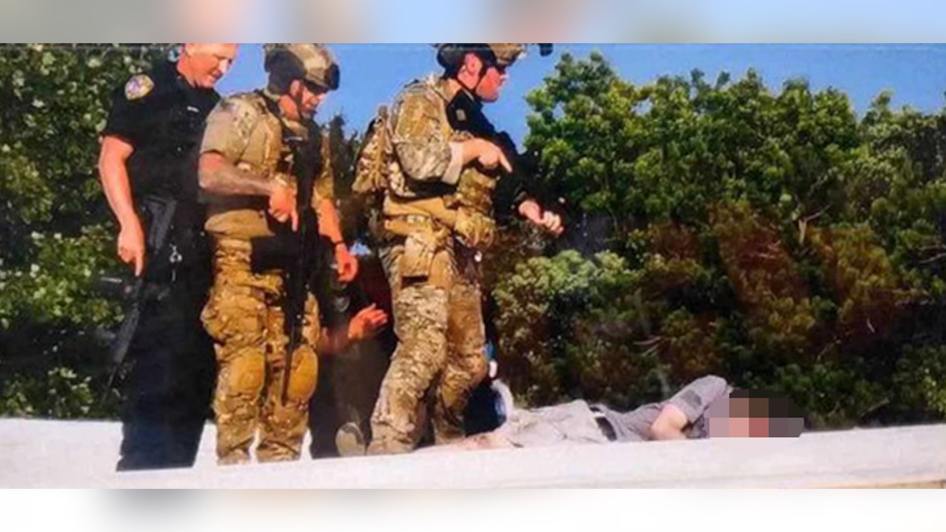 Armed men stand over the body of the would-be Trump assassin, whose face is blurred