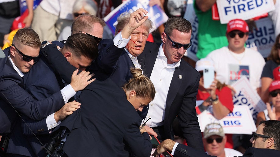 Donald Trump gesticula con la cara ensangrentada al sonar múltiples disparos durante un mitin de campaña