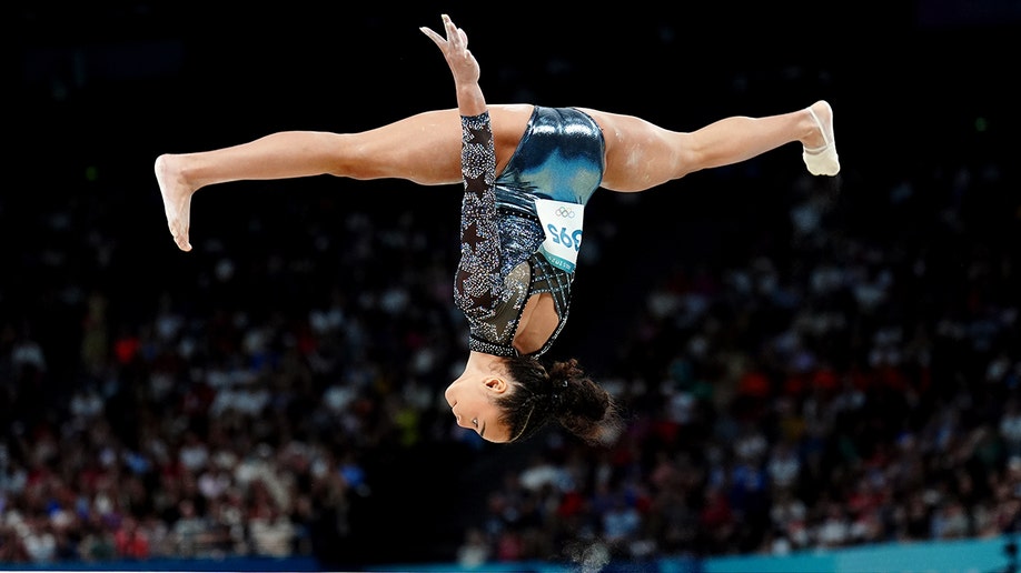 Hezley Riivera on the balance beam upside down with her legs outstretced