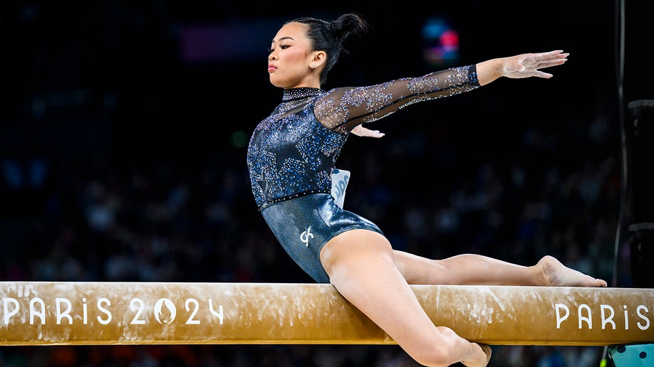 Suni Lee outstretches her arm on the balance beam