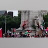 A person spray paints on the base of the Christopher Columbus Memorial Fountain as pro-Palestinian demonstrators protest near the US Capitol