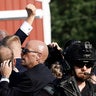 Donald Trump pumps his fist as he is rushed into a car