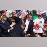 Donald Trump gestures with a bloodied face as multiple shots rang out during a campaign rally