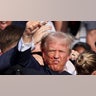 Donald Trump gestures with a bloodied face as multiple shots rang out during a campaign rally