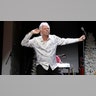 Joe Bonsall in a white patterned shirt puts his hand up to his ear while on stage in Tennessee