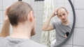 A man looking at his hair in the mirror in the bathroom - Fox News