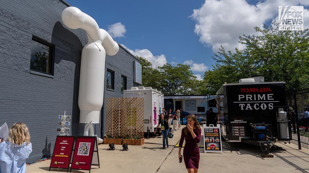 A taco truck, portable toilets and an abortion van parked next to a building