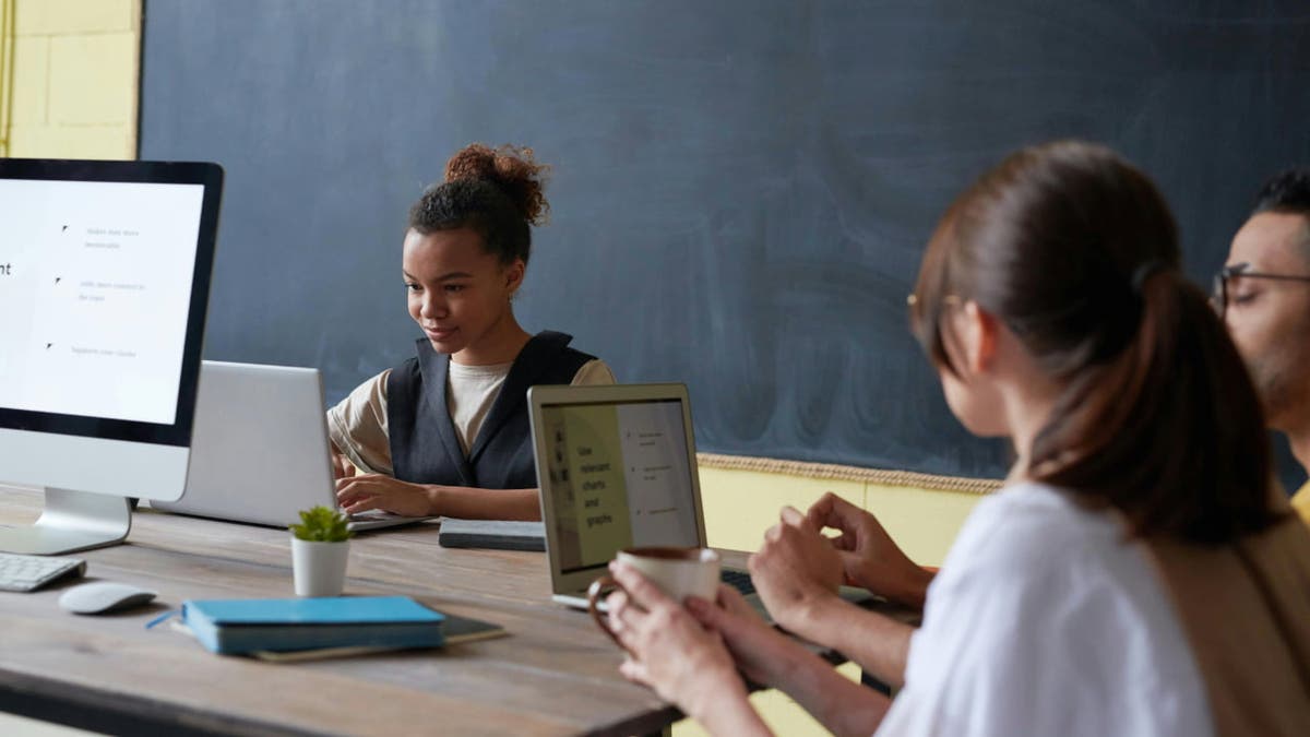 Students in a a classroom working on their laptops 