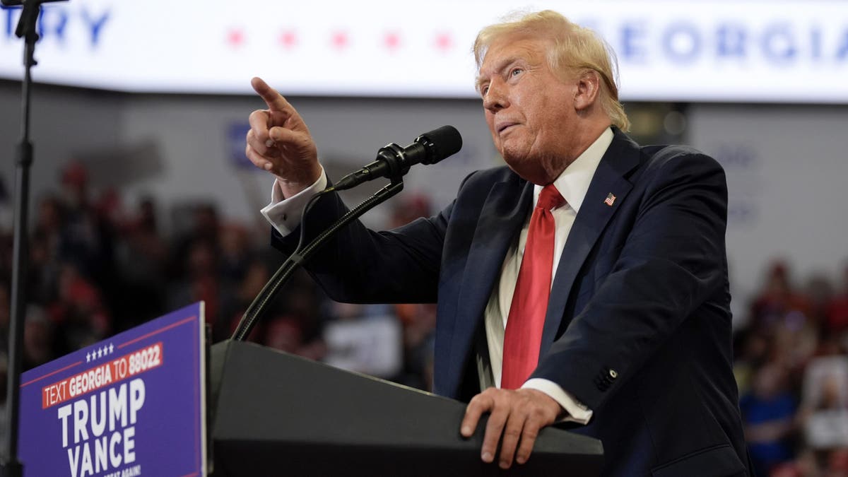 Donald Trump menunjuk podium rapat umum