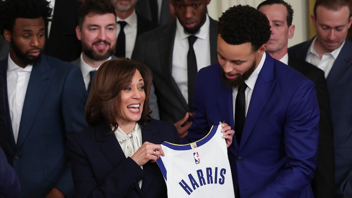 La estrella de los Golden State Warriors, Steph Curry, le presenta una camiseta a la vicepresidenta estadounidense, Kamala Harris.