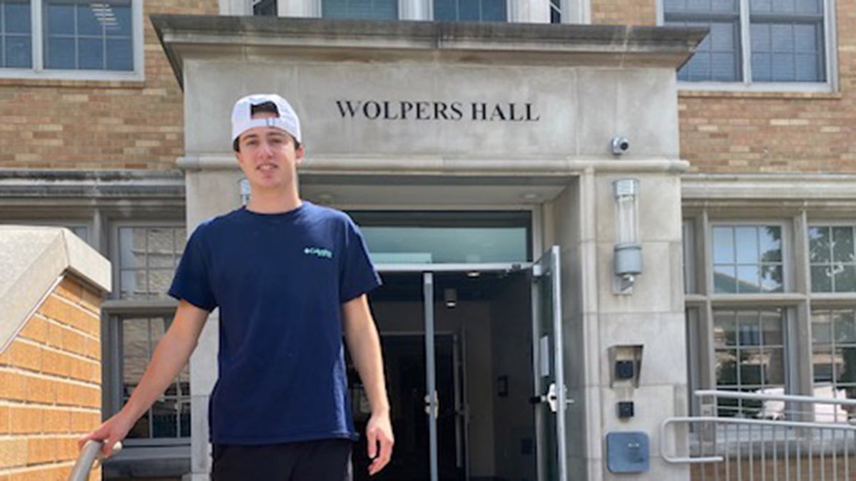 Danny Santulli stands in front of his college.