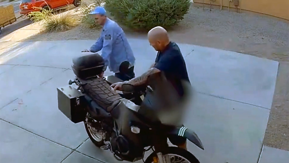 Two thieves attempting to steal a motorcycle, one with his pants falling down