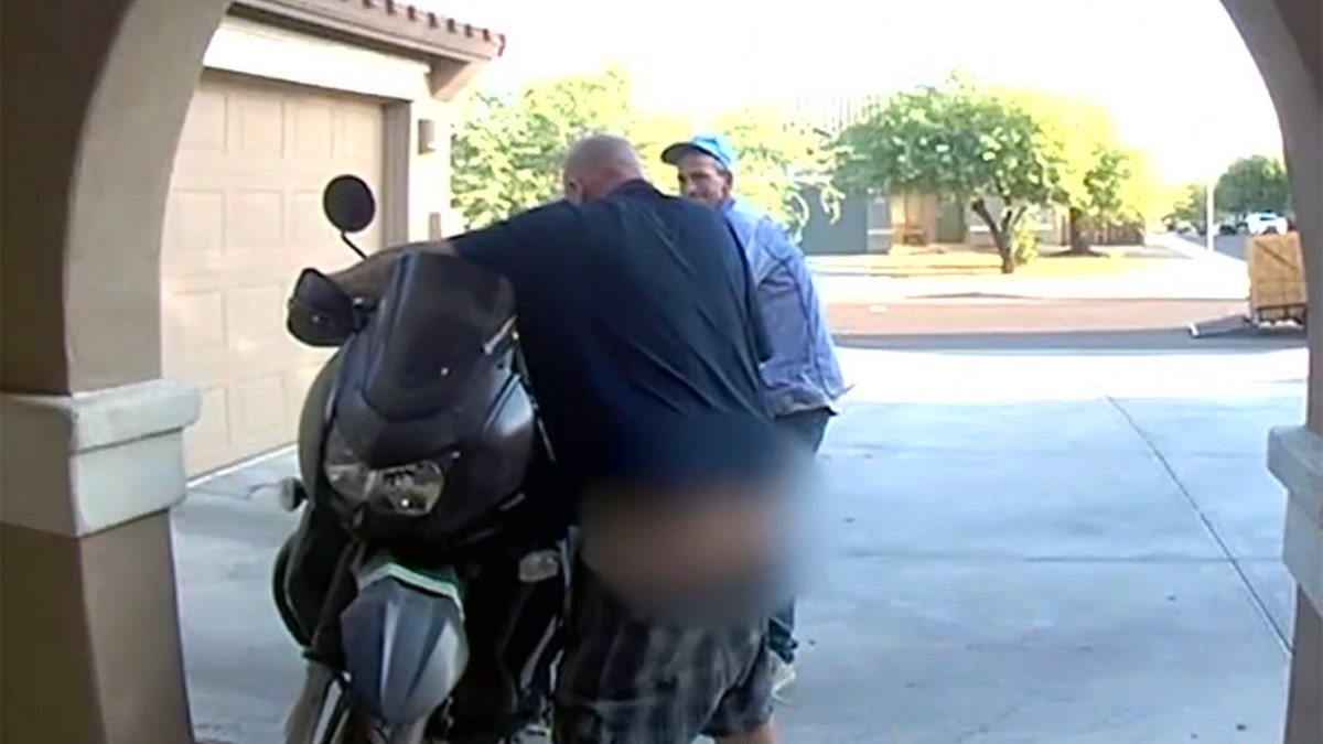 Dos ladrones intentando robar una moto, uno con los pantalones caídos